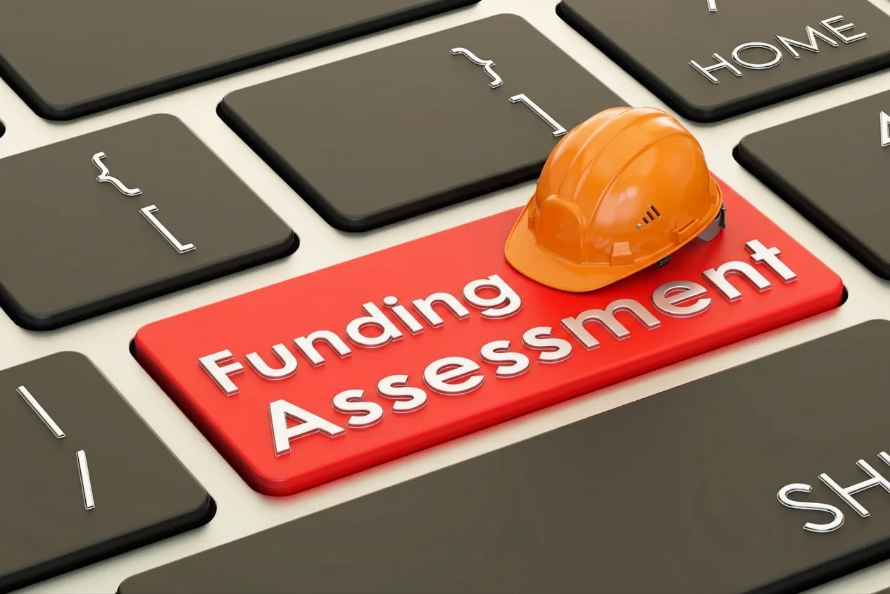 A miniature orange hard hat resting on a red keyboard key labeled Funding Assessment